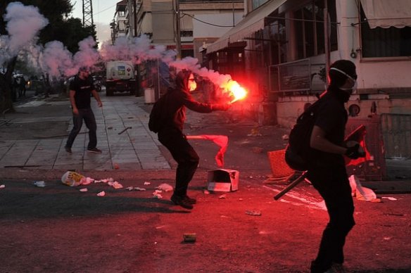 An anti-fascist protester lights a flare during clashes in the western Athens working class suburb of Keratsini on September 18, 2013. Photo Credit: LOUISA GOULIAMAKI