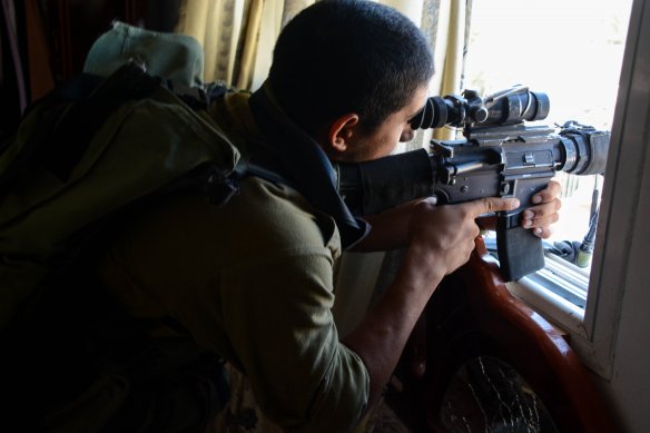 An Israeli paratrooper takes aim inside a Gazan building.  From the IDF flickr account.